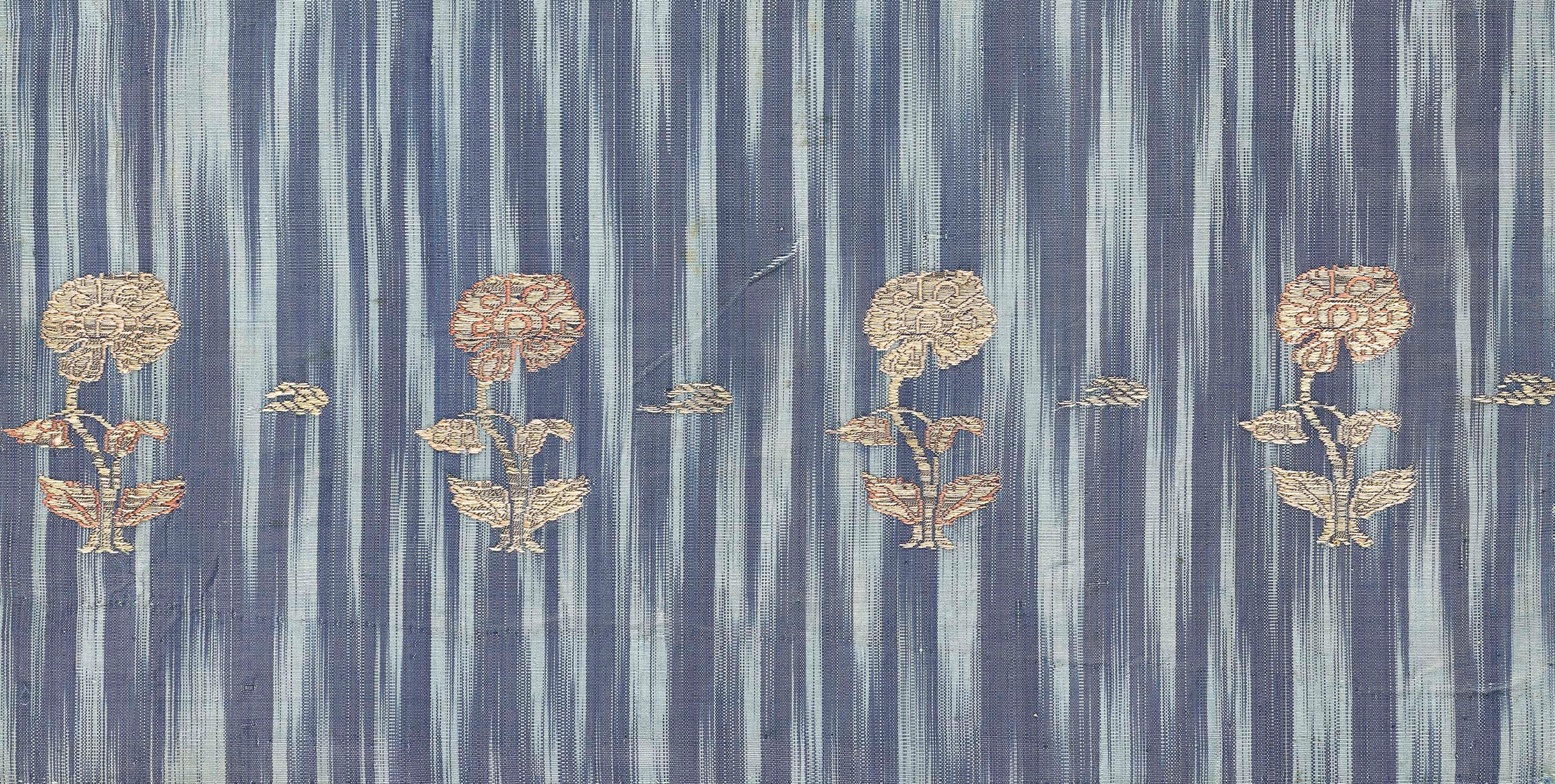 A detail of a textile with a blue crisscross pattern on a lighter blue ground. There are eight embroidered flowers in two rows.