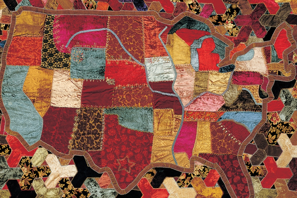 A multicolored quilt featuring an embroidered map of the United States