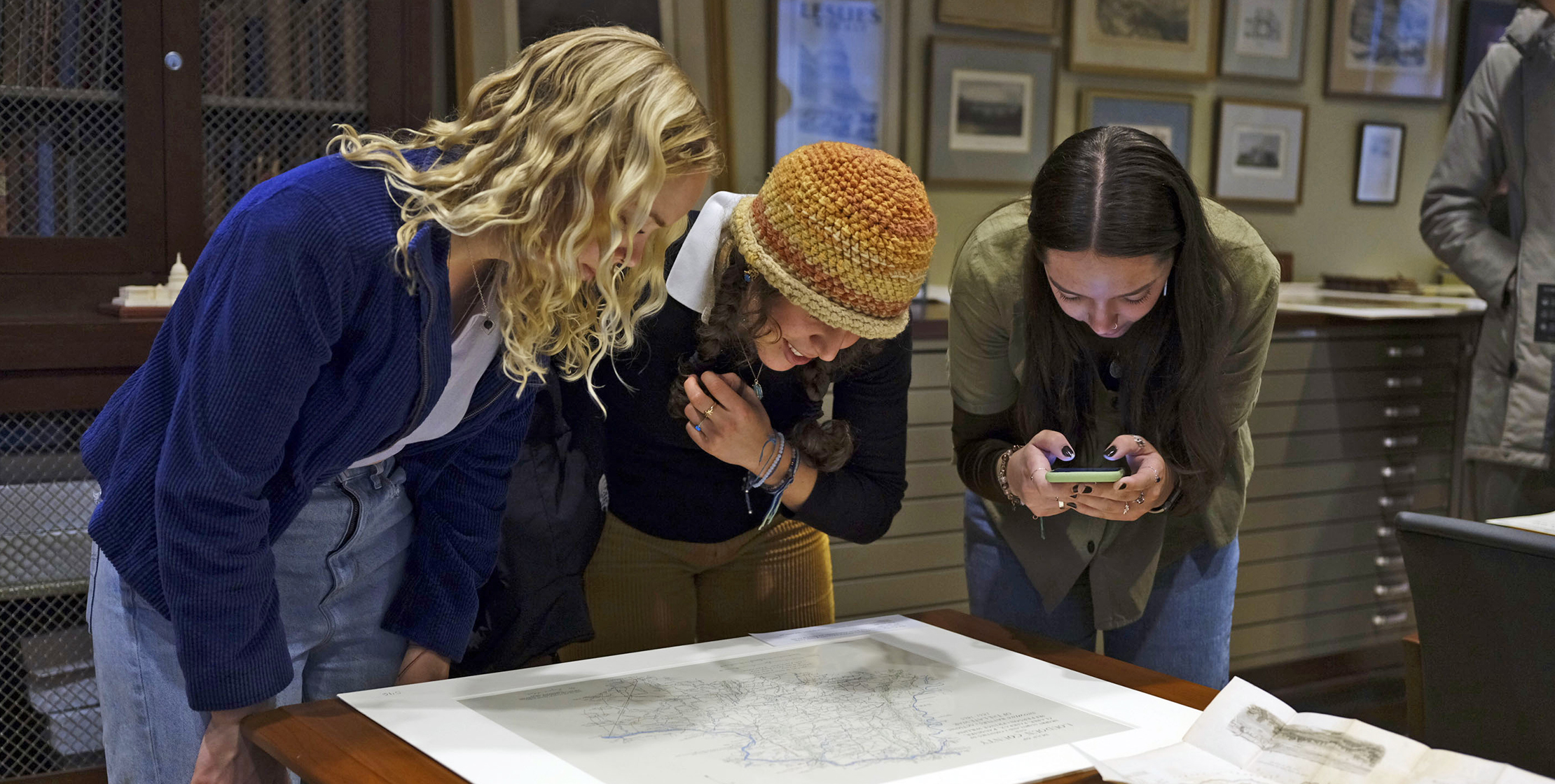 Three students examine a map from the collection 