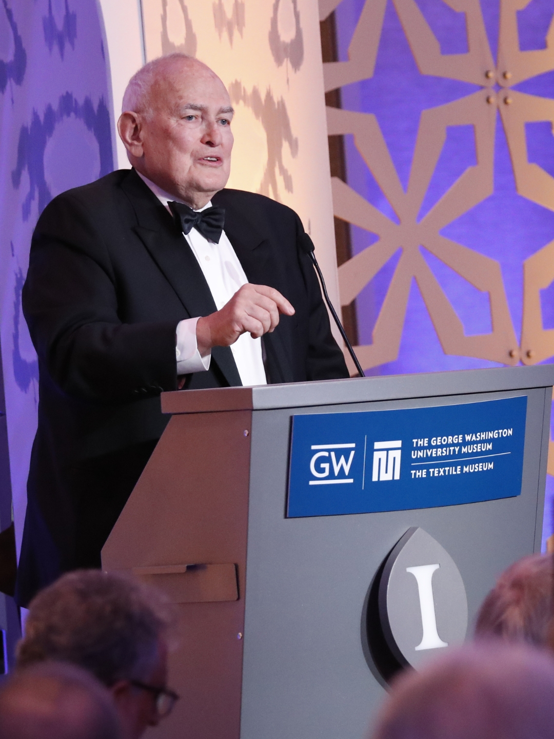 Guido Goldman presents at a podium during a black-tie event