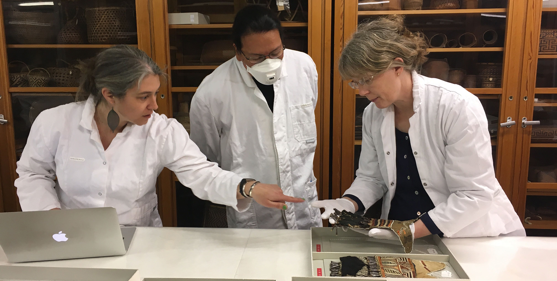 Three people in lab coats looking at an object