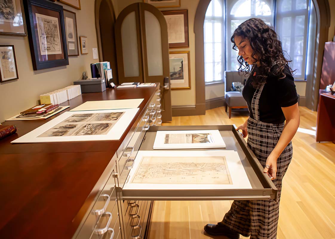 young woman pulls out a drawer of historical objects