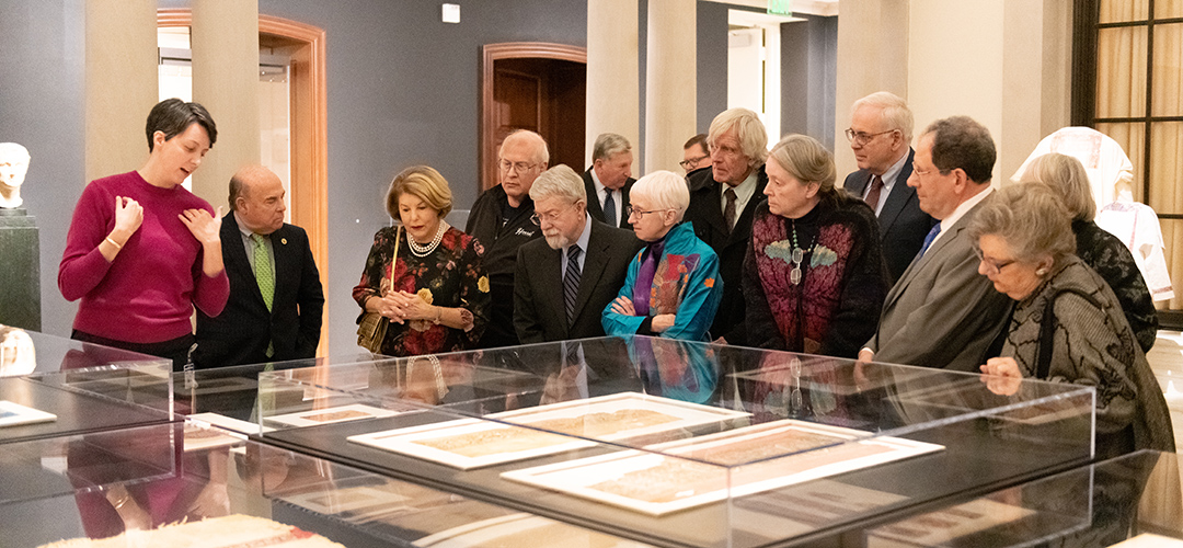 group of people gathered around a table looking at textiles
