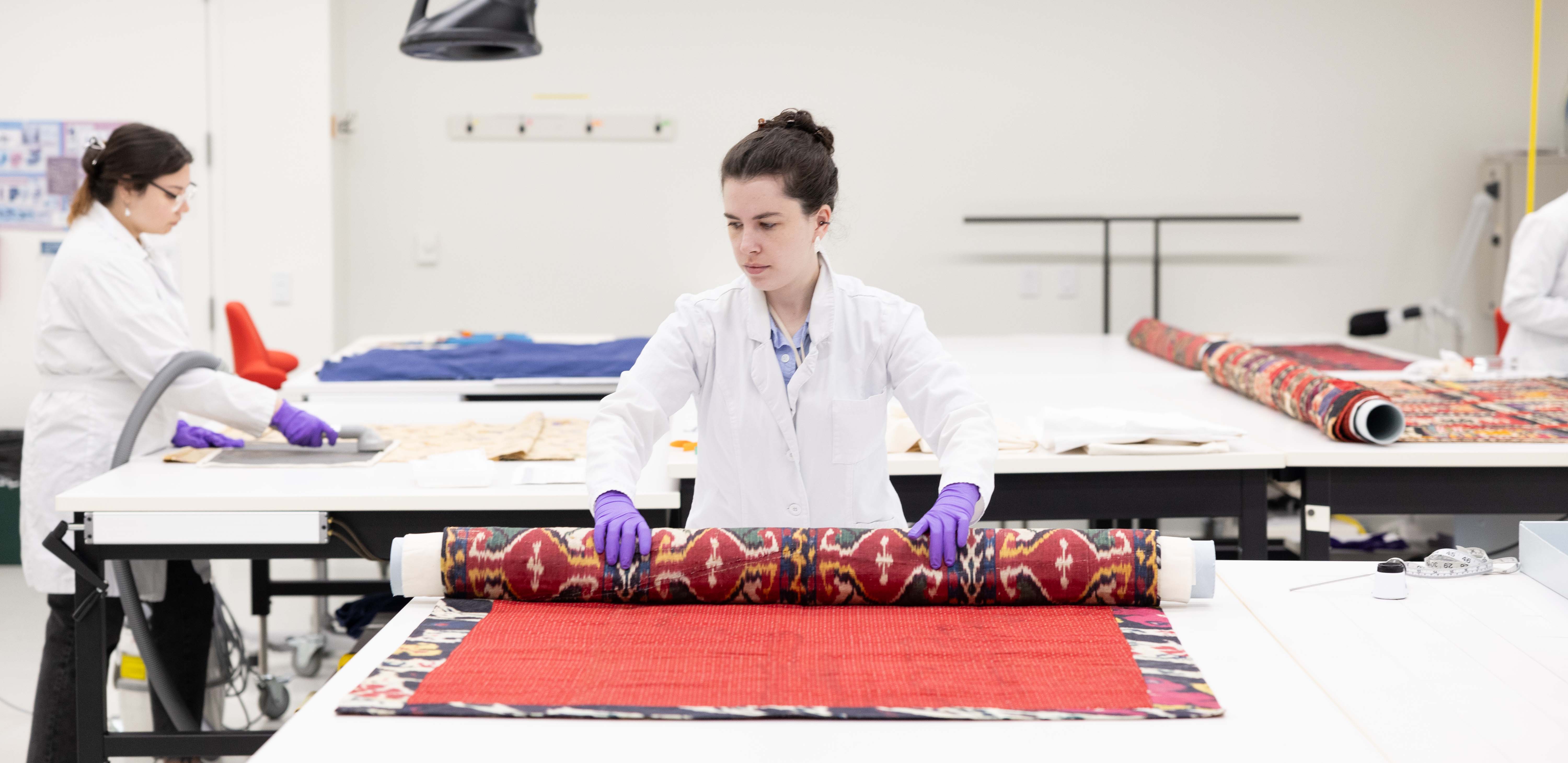 a woman in a white lab coat unfurls a large textile