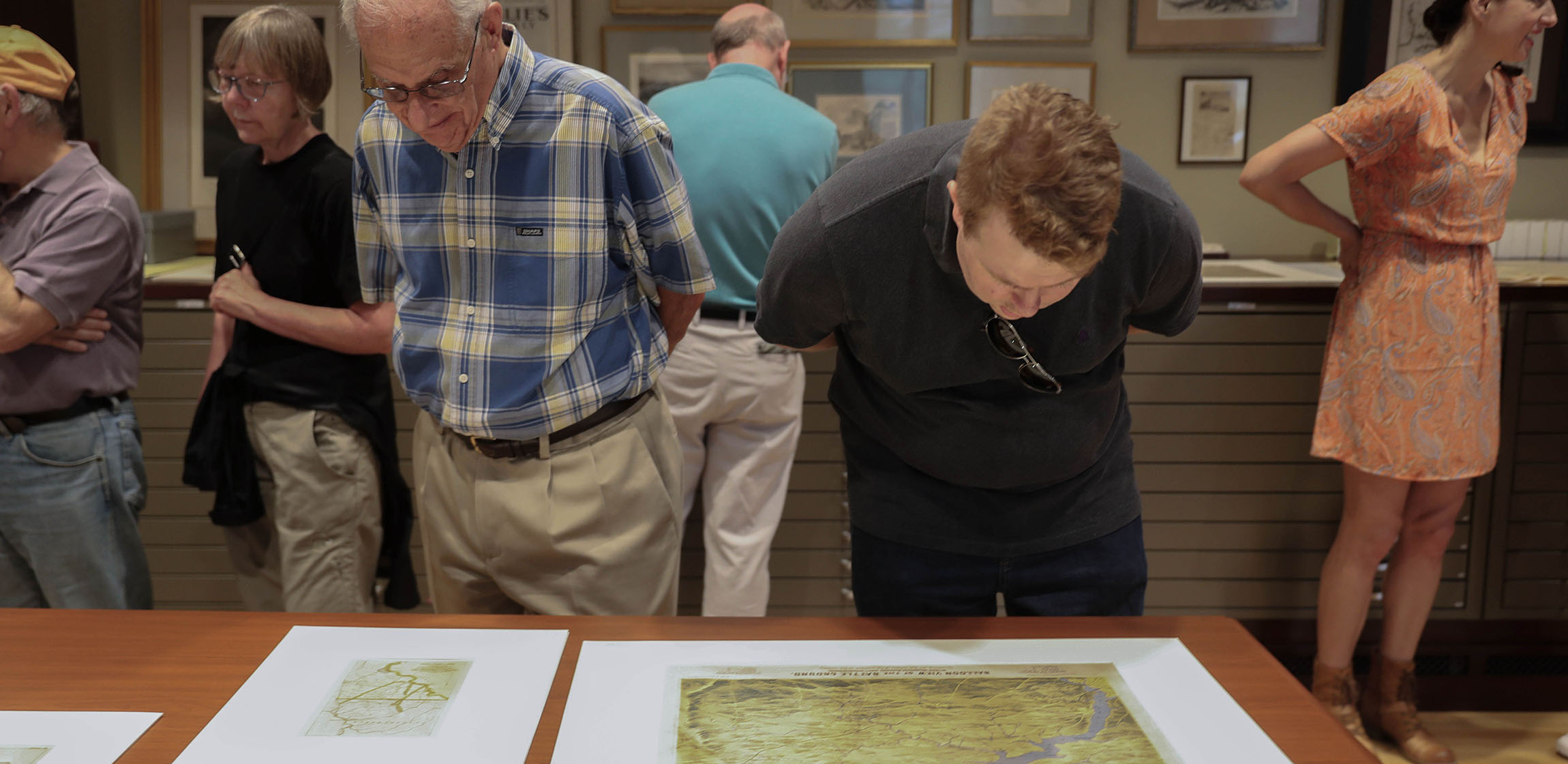 two men lean over to look at maps laid out on a table