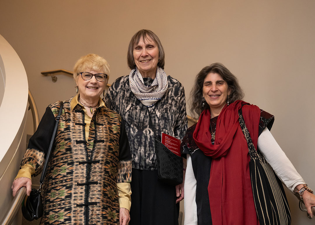 three women standing on a staircase pose for the camera