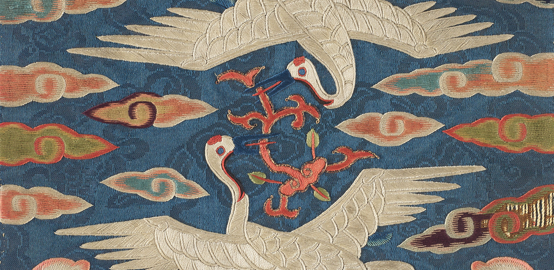 two embroidered cranes circle each other