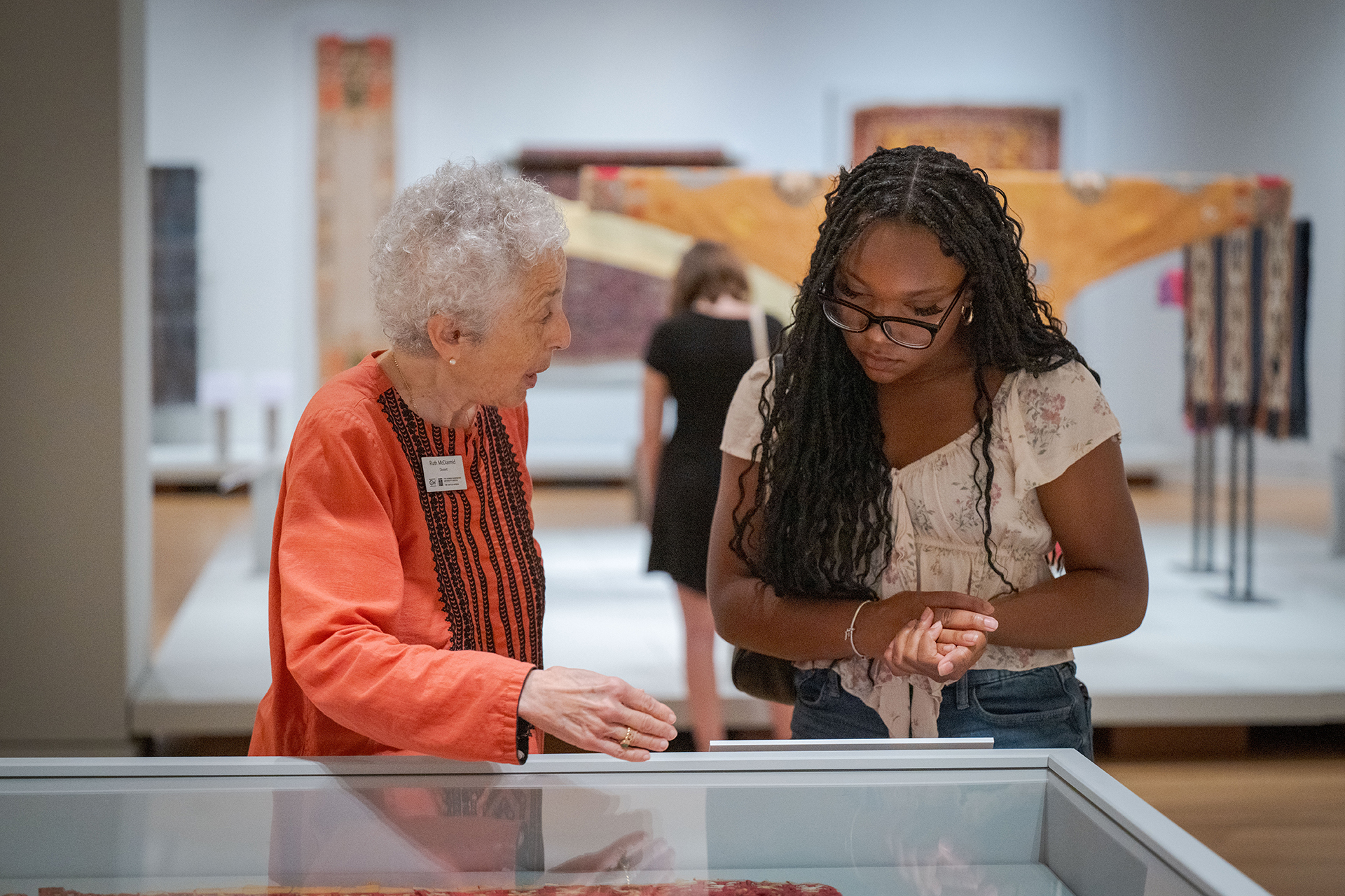 two women peer into a clear display case