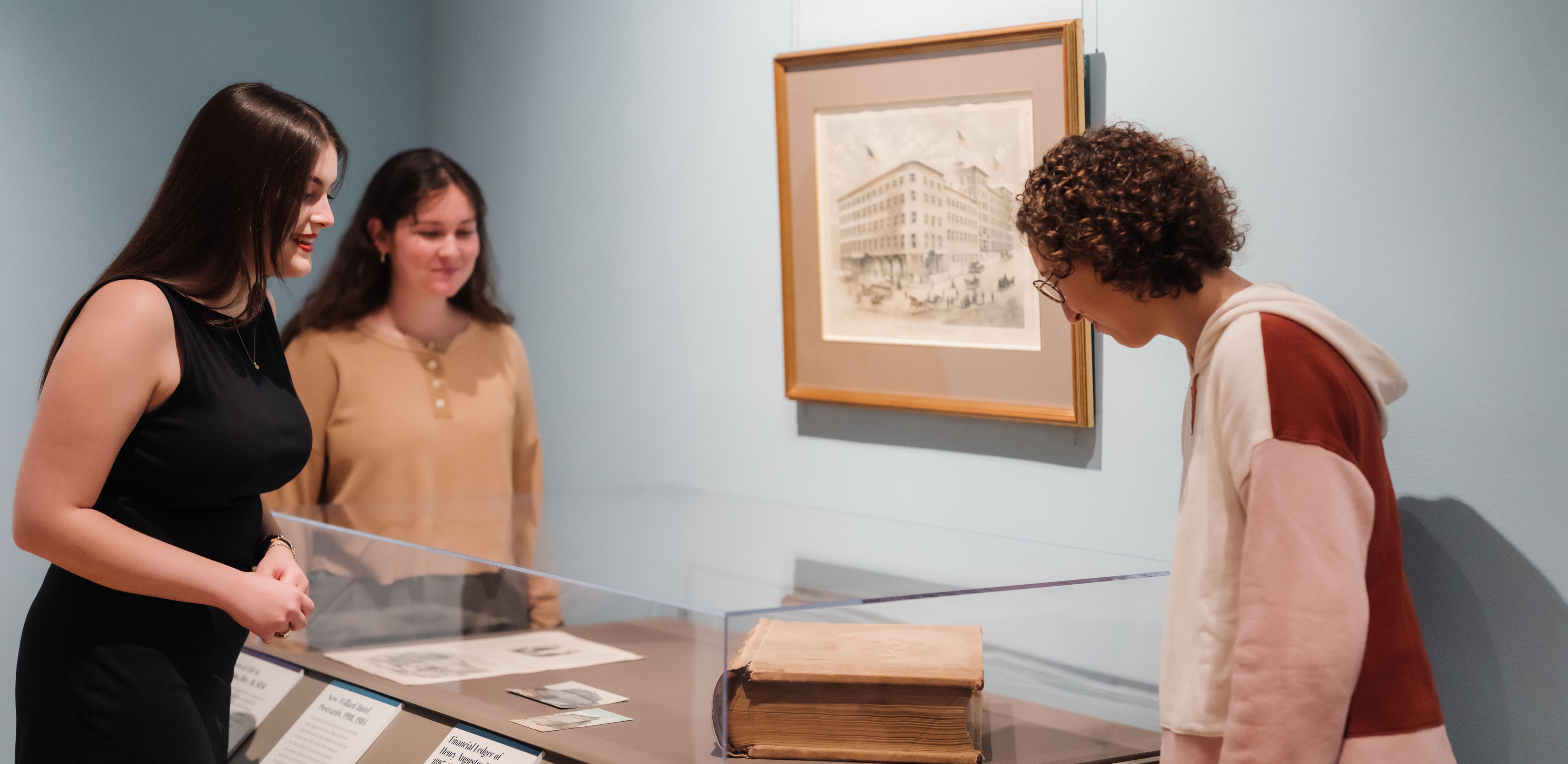 three women looking in a museum display case