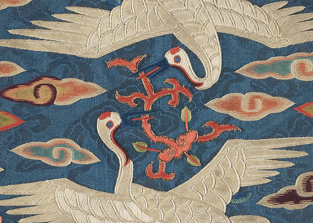 two embroidered cranes circling each other