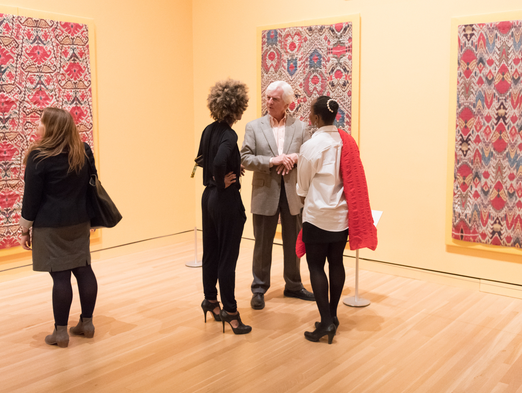 Four visitors look at colorful artworks in gallery