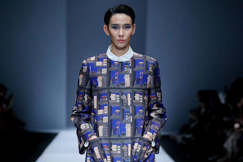 Korean woman on the runway modeling matching blue jacket and trousers with patterns inspired by Korean architecture