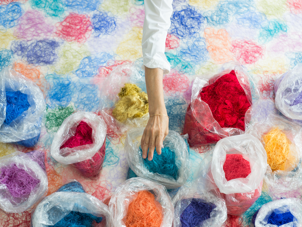 Hand reaching into bags of colorful thread