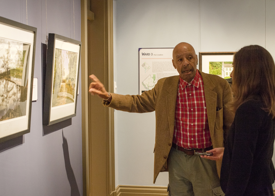 An artist points to his work in the exhibition
