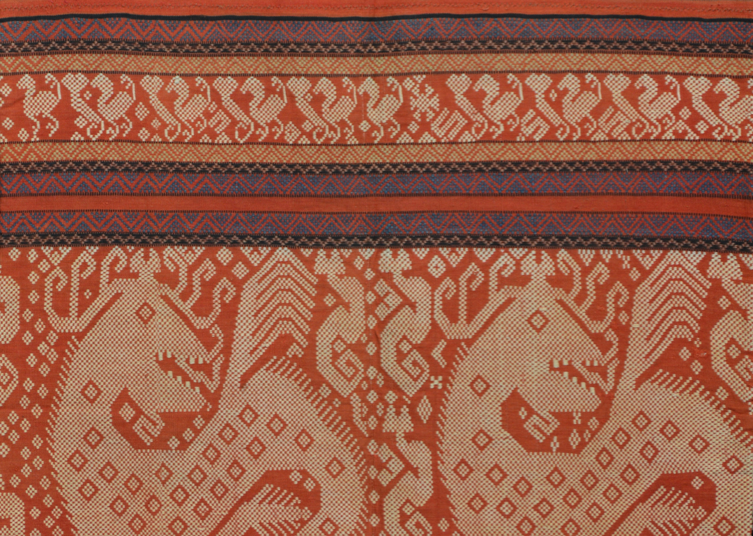 Detail of an orange textile with detailed horizontal bands at the top and recurring dragon motifs at the bottom