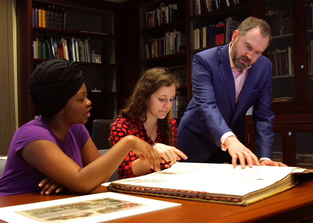 Three people examining at a book