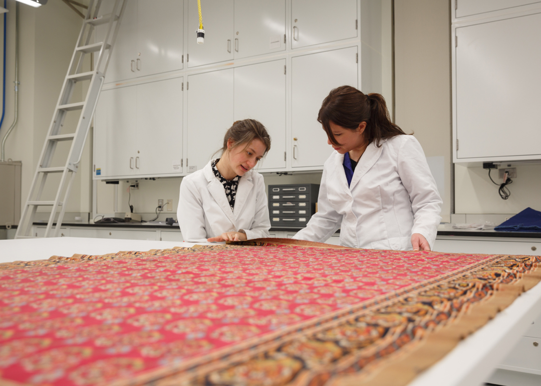 2 women with a large red rug