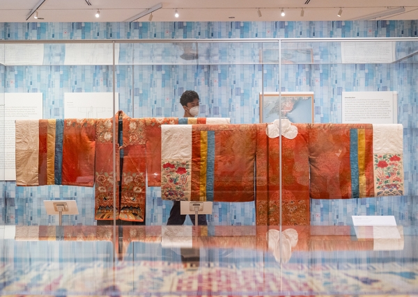 A museum visitor looks at two traditional, red Korean robes on display