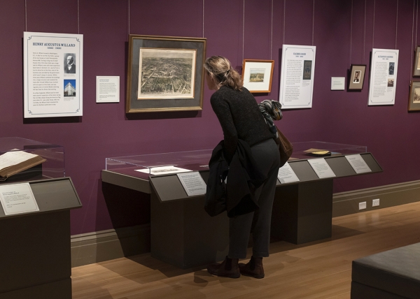 A museum visitor examines a historical print on display