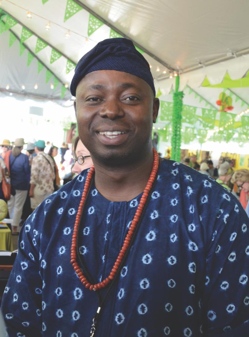 Portrait of a Nigerian man wearing an indigo-dyed jacket and cap, and an orange beaded necklace