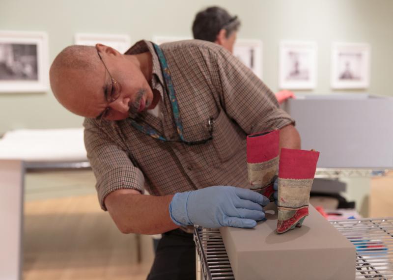 Man places Chinese shoes in a display case