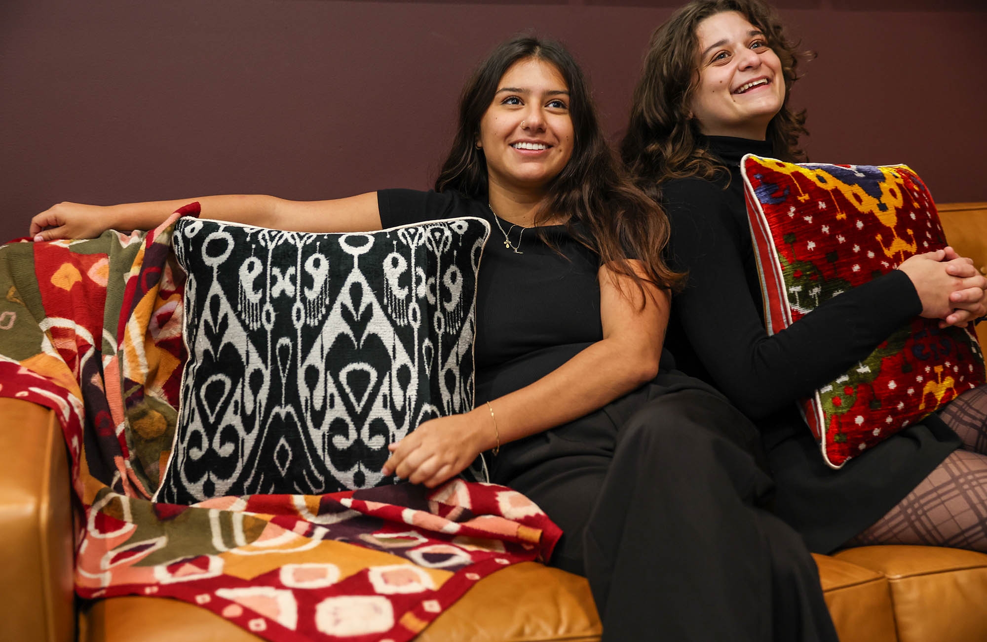 two woman smiling holding colorful pillows 
