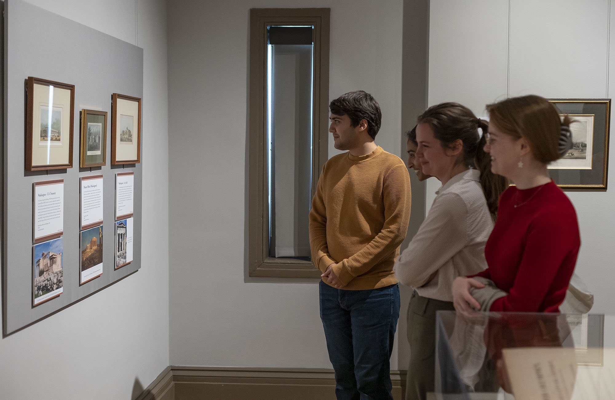 students stand admiring objects on a gallery wall