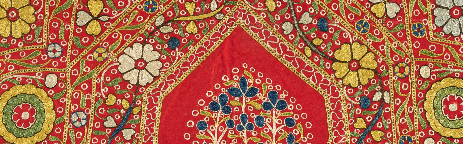 detail of an ornately decorated textile with red ground and colorful floral designs