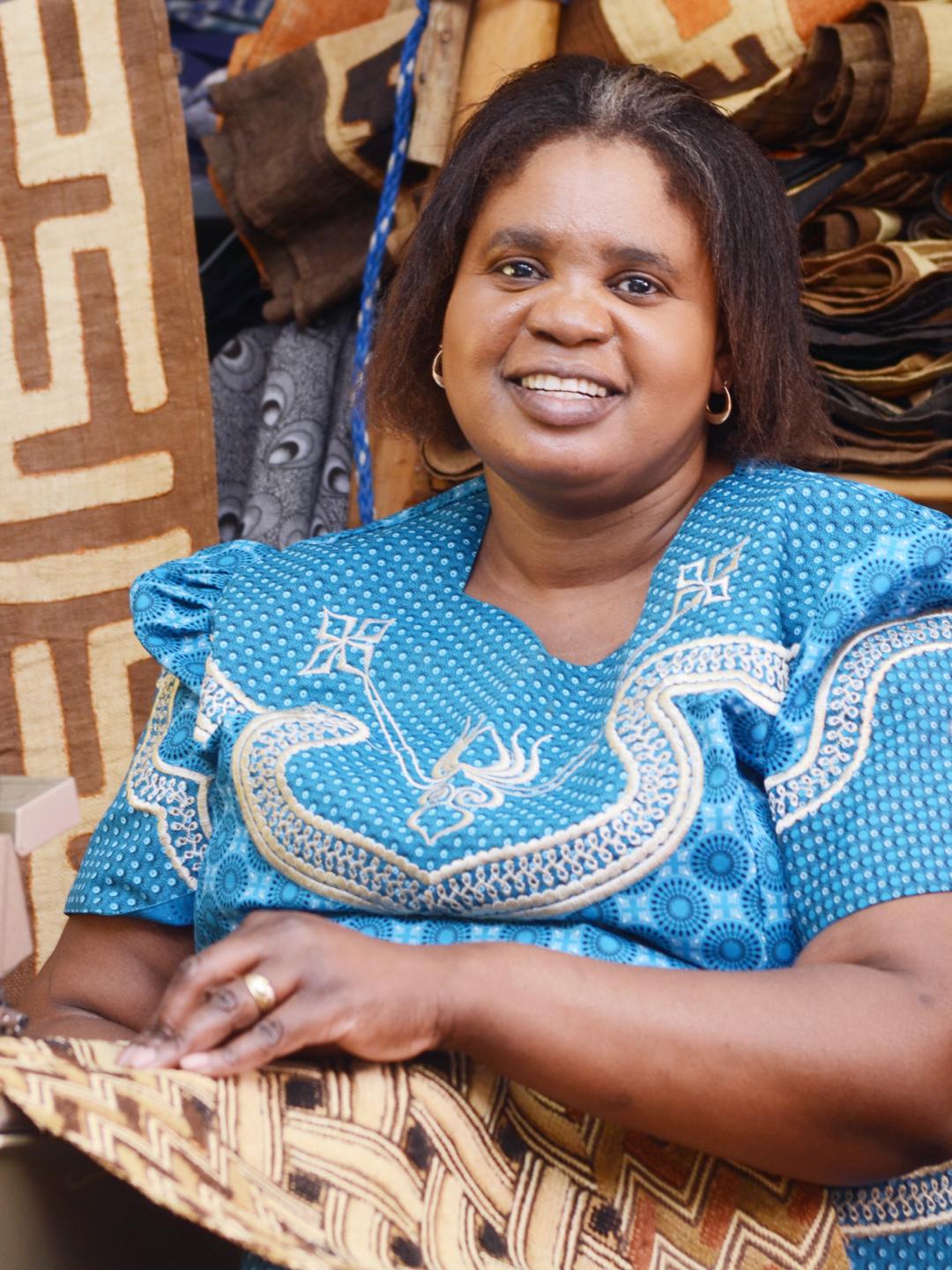 Woman seated with raffia cloth behind her