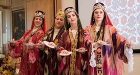 Four women dancers wearing colorful Uzbek ikat robes and headdresses