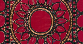 red textile with central medallion shaped like a sunflower