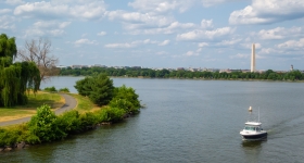 a oat cruising down the anacostia river with the washington monument in the background