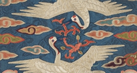 two embroidered cranes circle each other