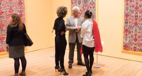 Four visitors look at colorful artworks in gallery